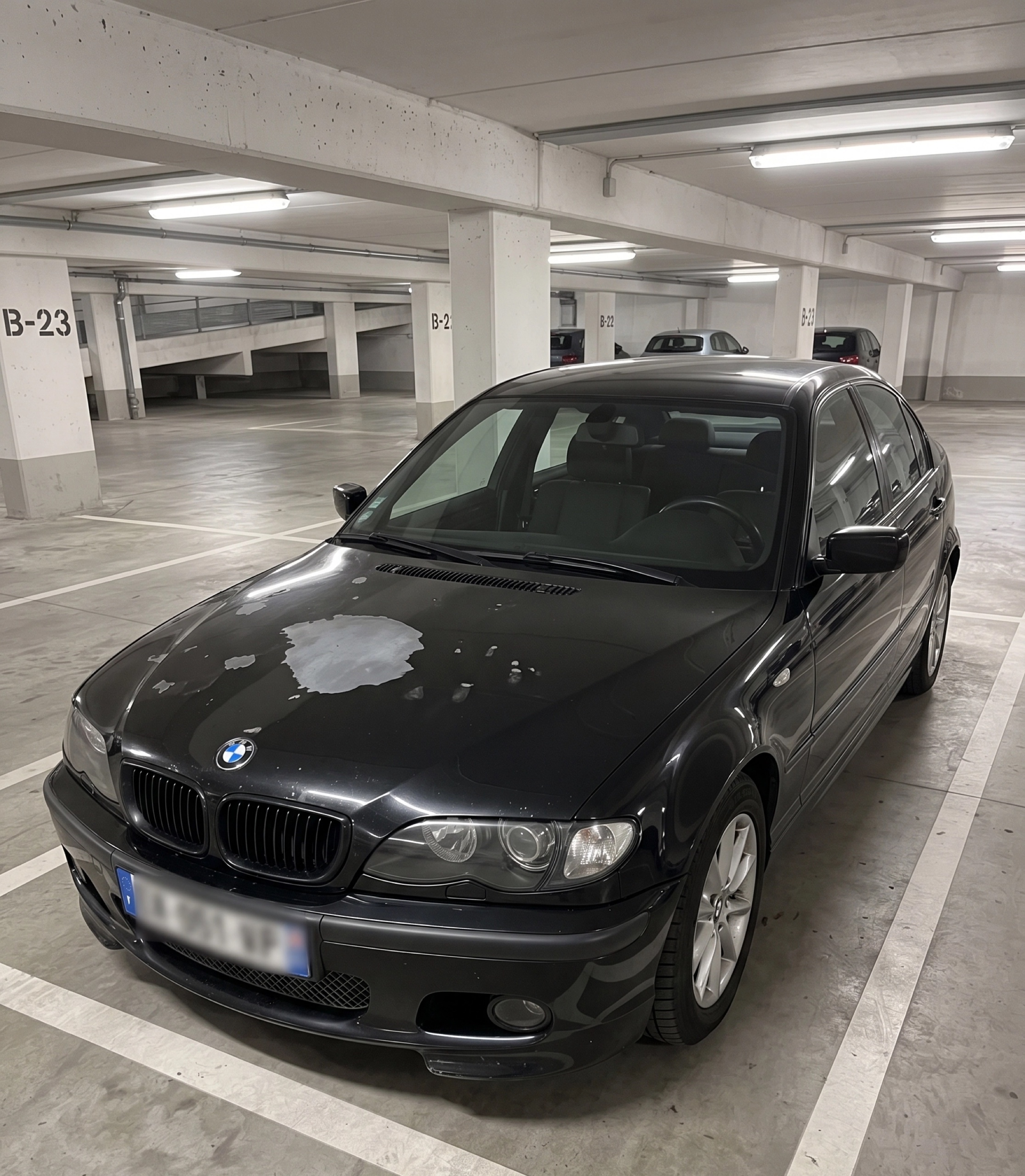Black BMW with paint damage in a garage